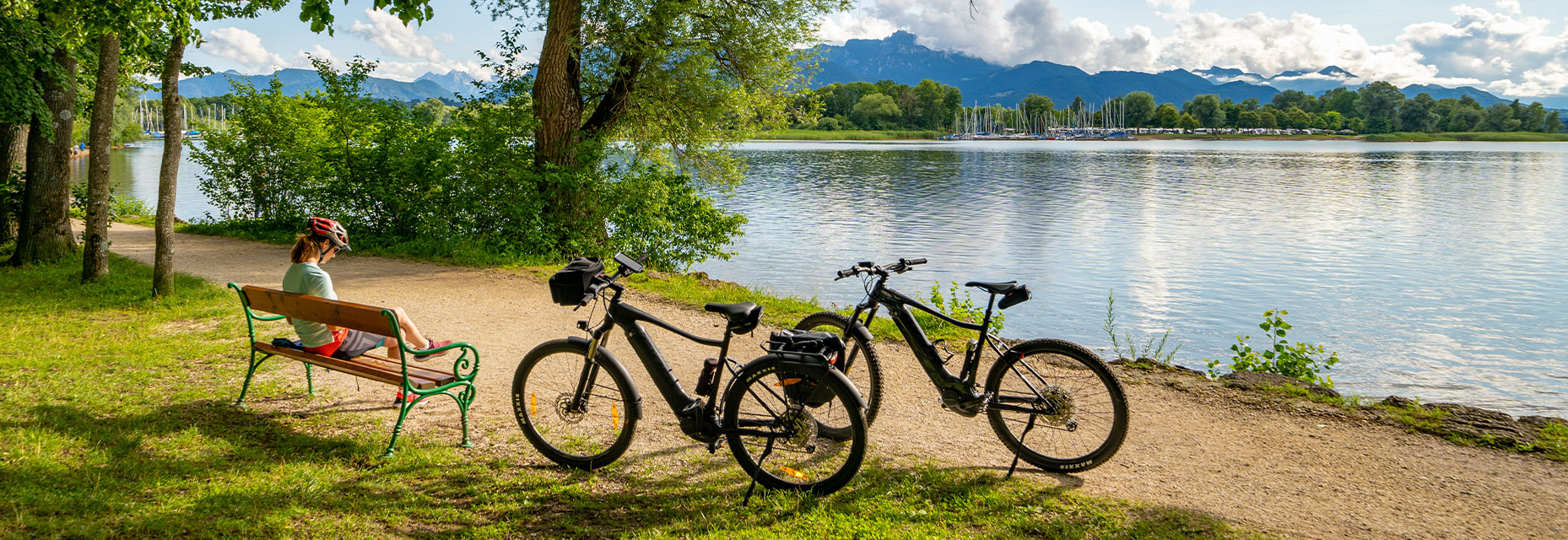 zwei Räder und Radfahrer auf Bank mit See